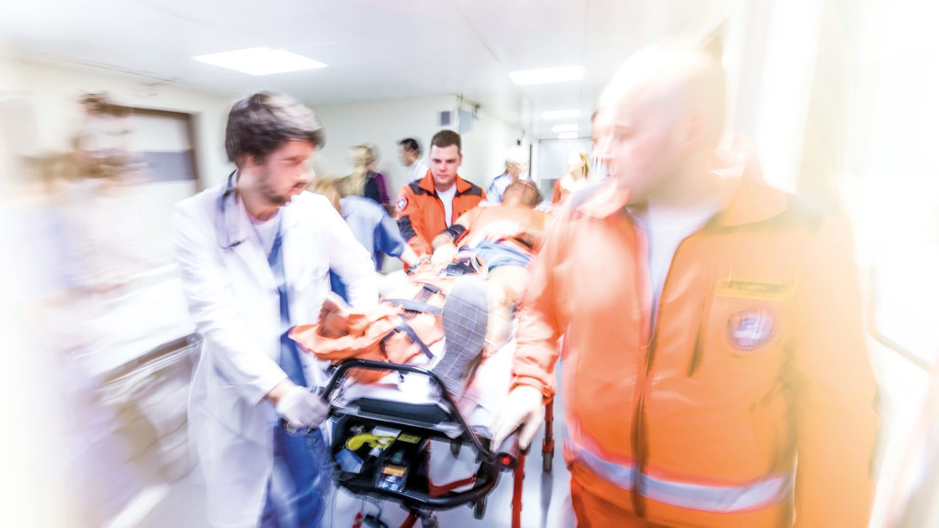 Paramedics and doctor pushing stretcher with injured patient